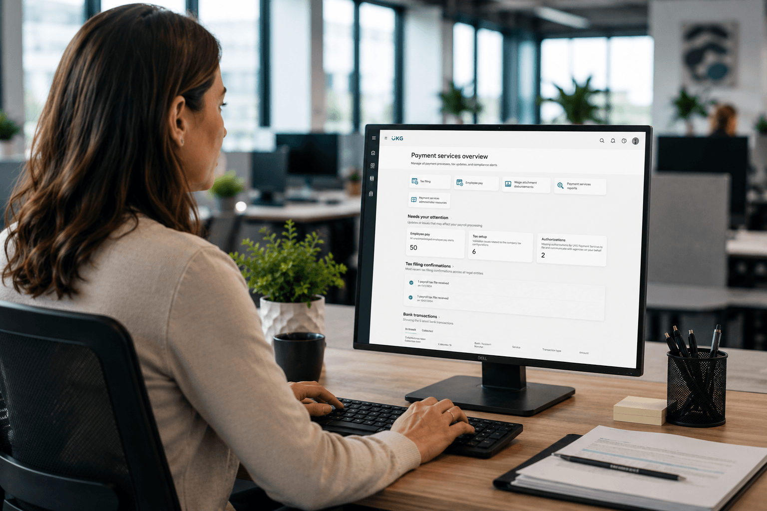 Payroll administrator using the unified UKG payment services overview on a desktop monitor